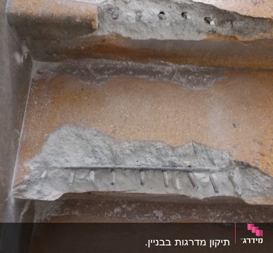 ברגים חשופים בקיר בטון מתקלף במהלך שיפוץ